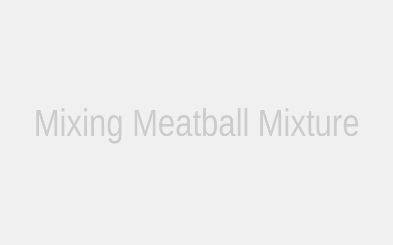 A pair of hands gently but thoroughly mixing ground beef, vegetables, and seasonings in a large bowl, demonstrating the proper technique for combining the meatball mixture.
